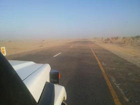 woestijnzand waait over asfaltweg